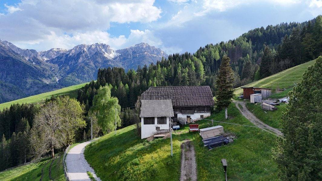Traditionelles Bauernhaus in idyllischer Lage, umgeben von grünen Wiesen und einer beeindruckenden Bergkulisse.