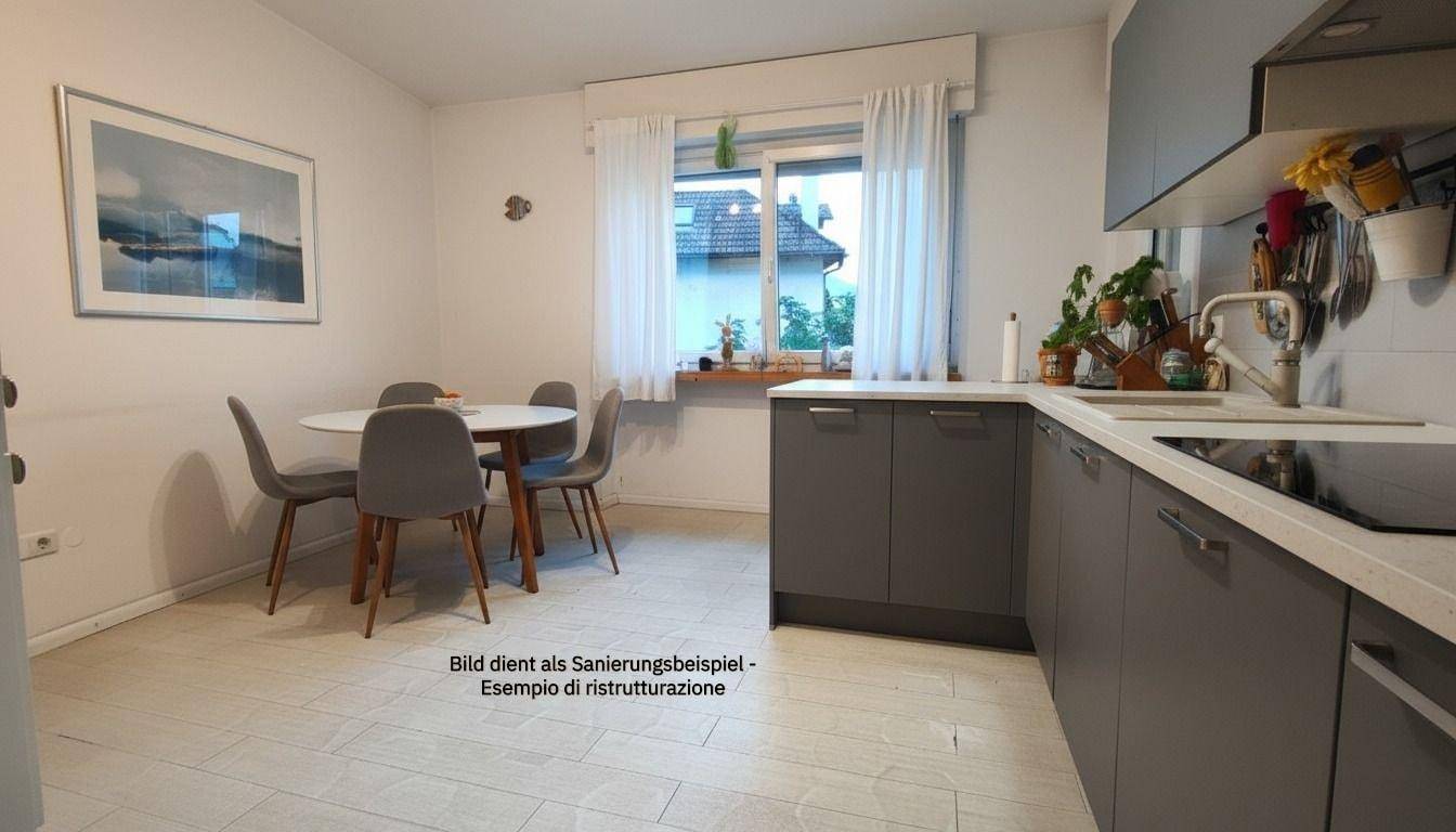 Helle Wohnküche mit grauen Schränken, Esstisch und Fenster mit Blick ins Grüne, funktional und einladend.