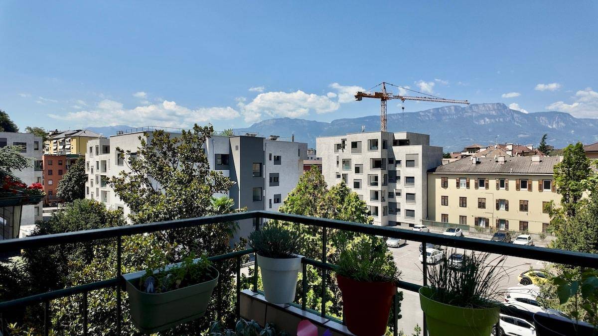 Balkon mit Pflanzen und weitem Blick über die Stadt auf die umliegenden Berge.