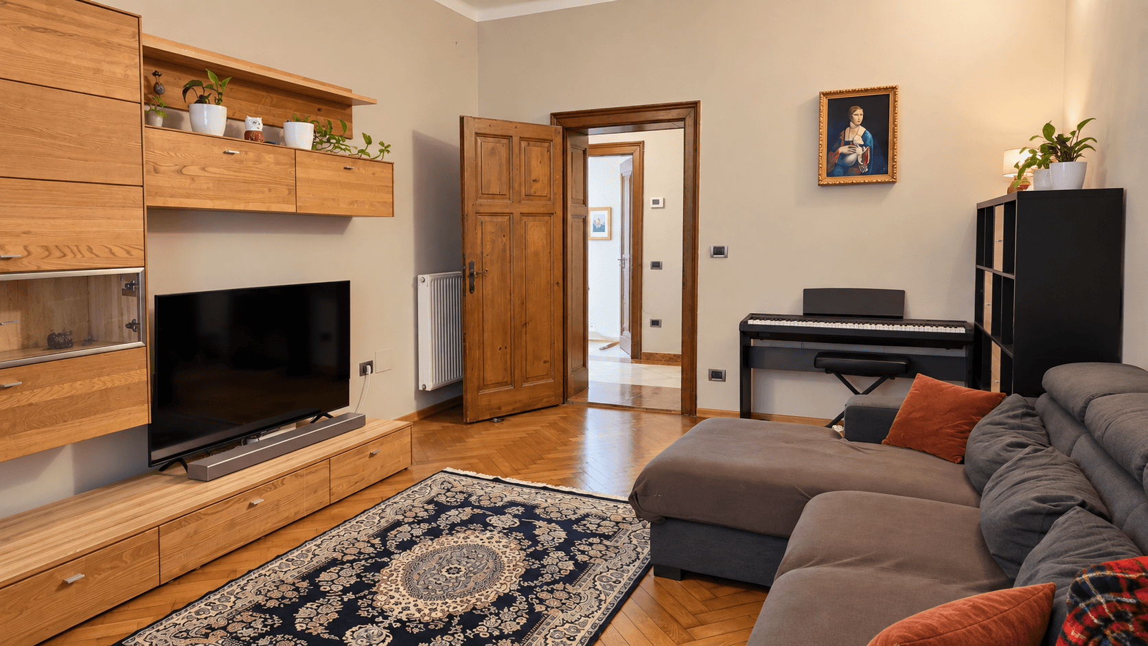 Wohnzimmer mit Holzboden, TV-Möbeln und einem Durchgang zu weiteren Räumen.