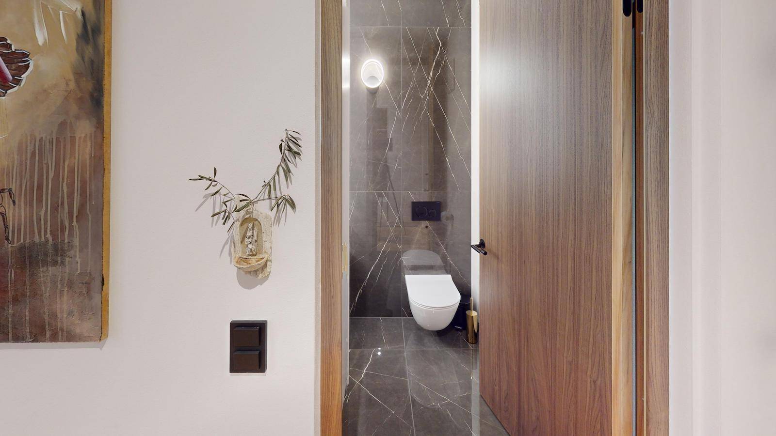 Modernes Gäste-WC mit dunklen Marmorfliesen und wandhängendem WC.