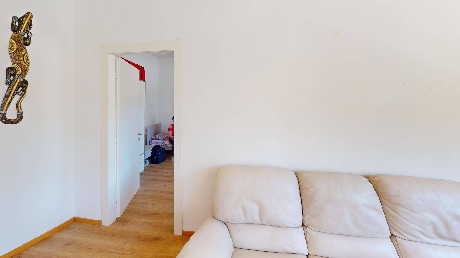 Wohnzimmer mit beigem Sofa und Blick in einen angrenzenden Raum.
