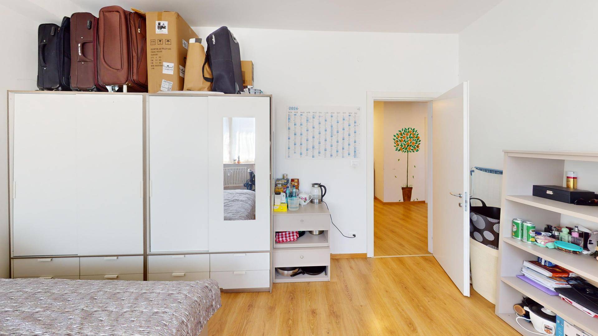 Schlafzimmer mit Holzboden, großem Kleiderschrank und Zugang zum Flur.