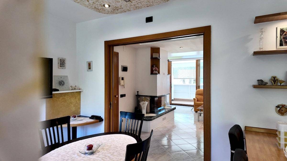 Essbereich mit Holztisch und Stühlen, offen zum Wohnzimmer mit Kamin.