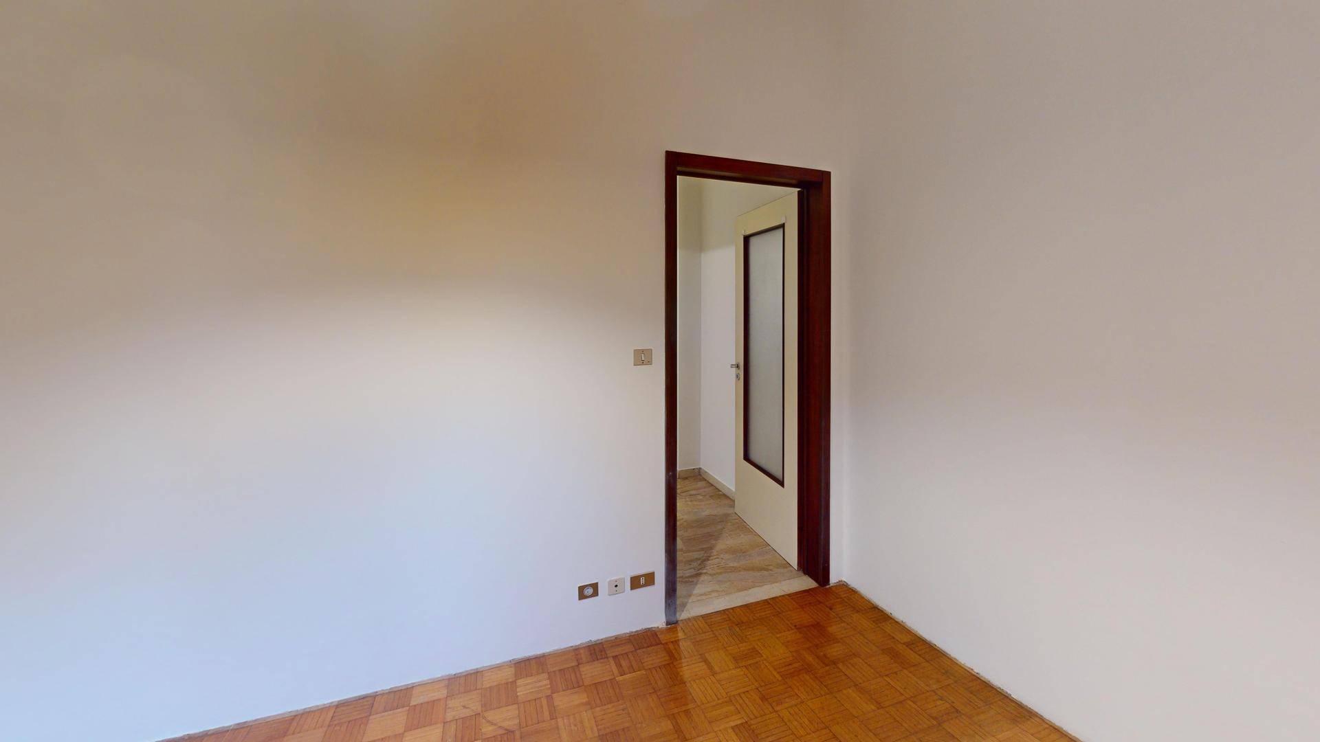 Helles Zimmer mit Parkettboden und einem Fenster, das einen angenehmen Blick ins Grüne bietet.