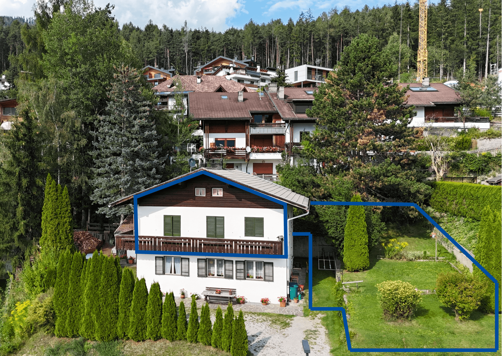 Luftaufnahme eines charmanten Hauses mit Garten, umgeben von viel Grün und Wald, in einer ruhigen Wohngegend.