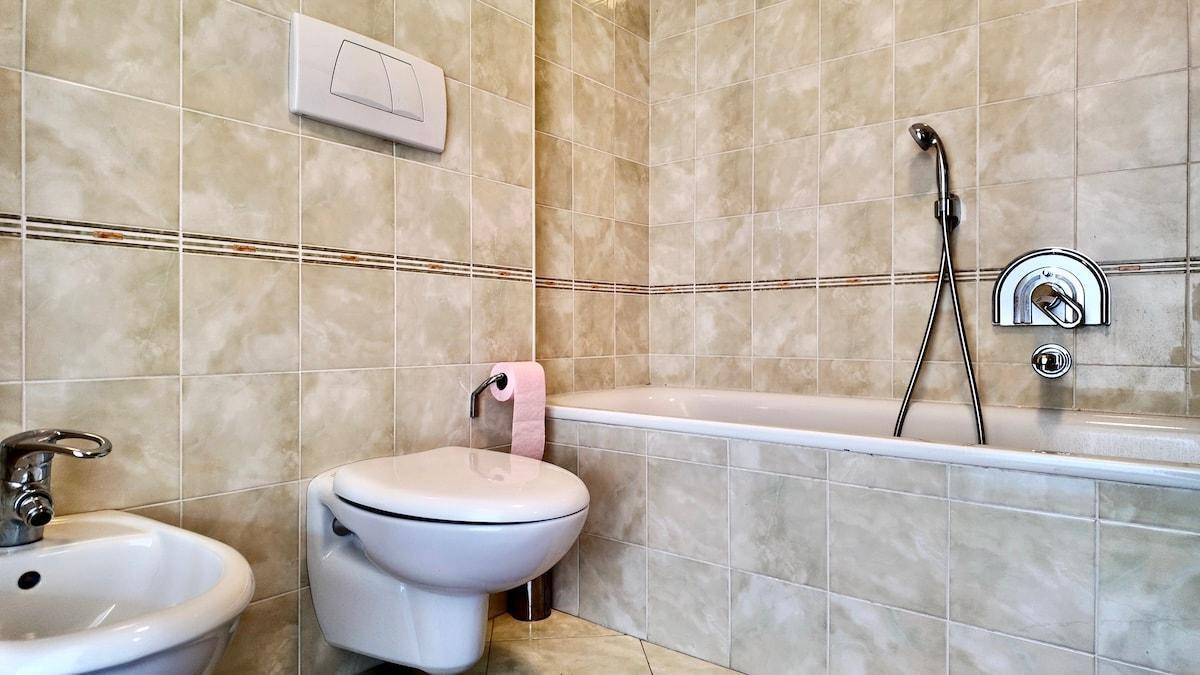 Badezimmer mit Badewanne, WC, Bidet und beigefarbenen Fliesen.