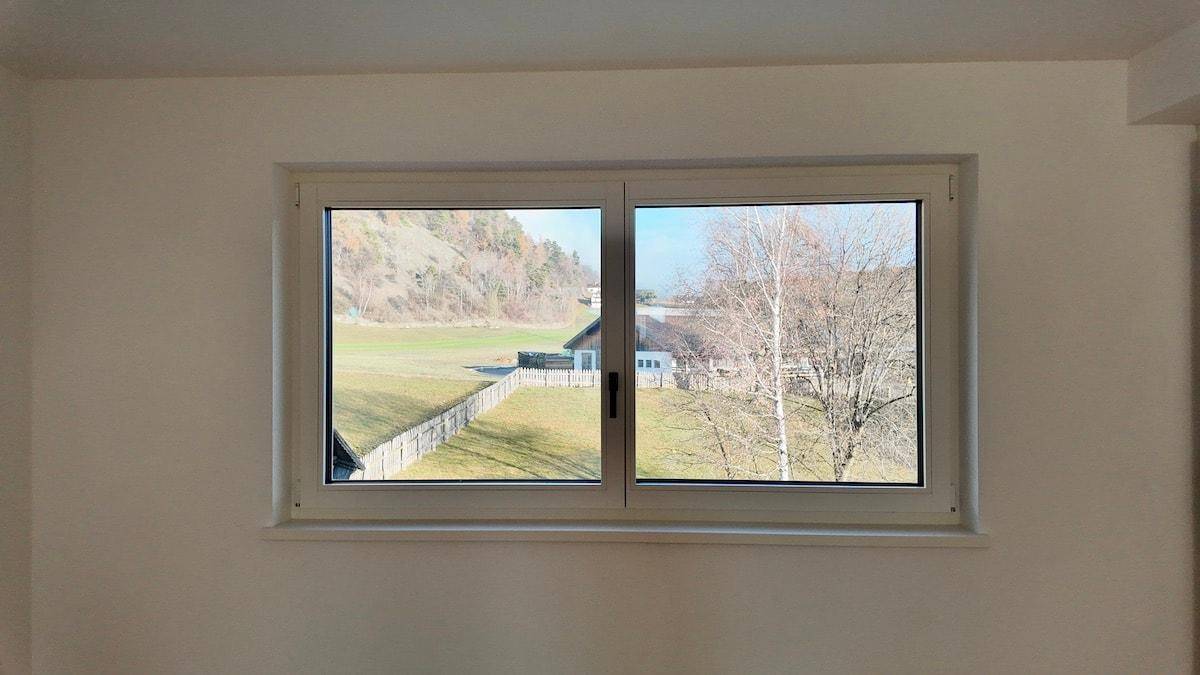 Fenster mit Blick auf grüne Landschaft und Bäume, das viel Tageslicht hereinlässt.