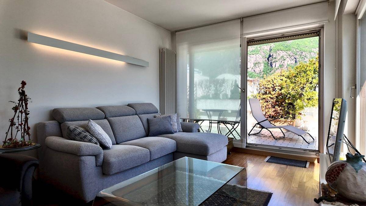 Helles Wohnzimmer mit bequemer Couch, Holzboden und Zugang zu einer Außenterrasse.