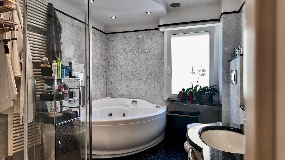 Modernes Badezimmer mit Whirlpool-Badewanne, Dusche und Marmorfliesen.