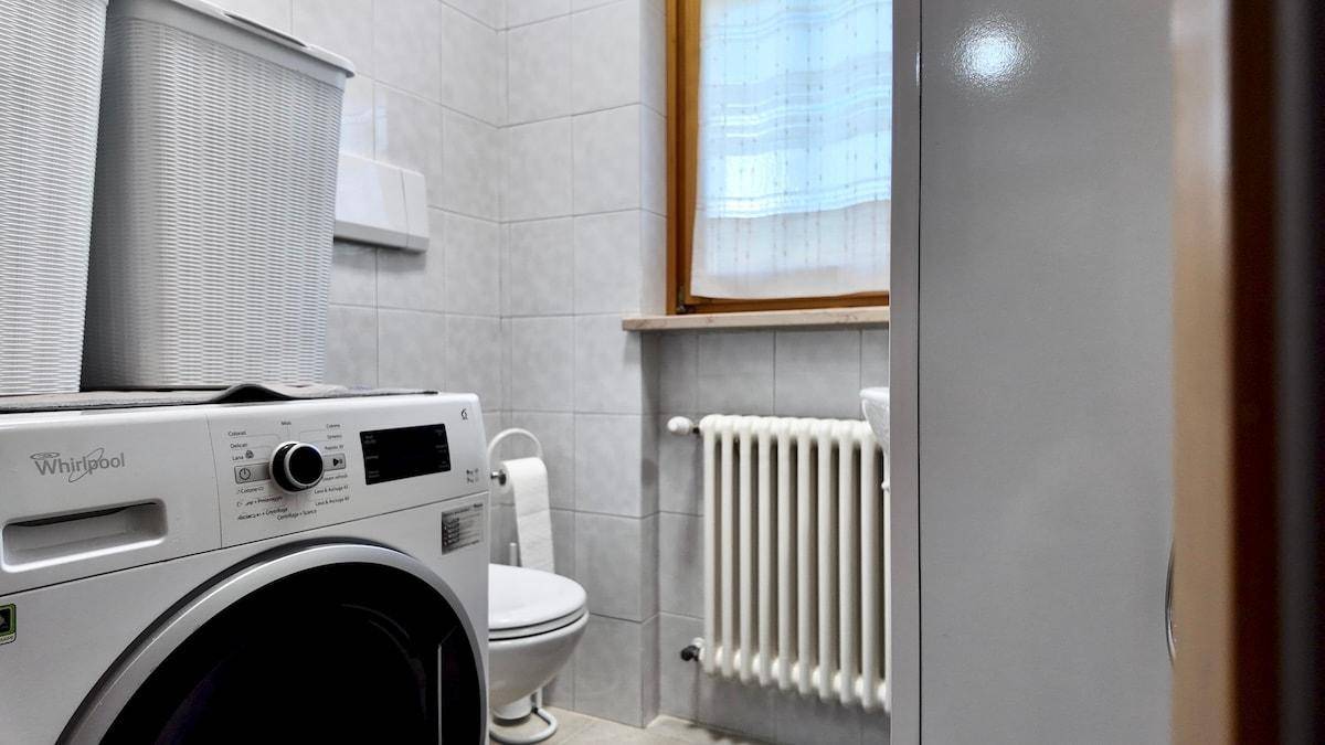 Waschküche oder Badezimmer mit Waschmaschine, WC und Fenster.