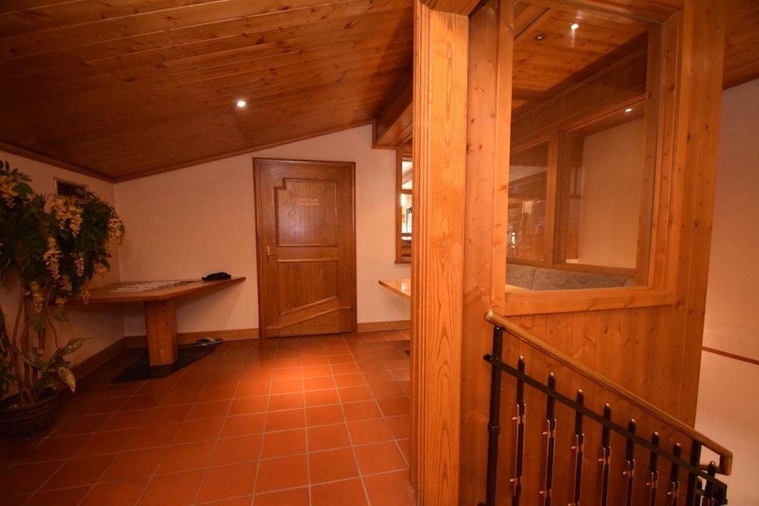 Heller Flur mit Holzvertäfelung, Terrakottafliesen und einer schrägen Decke im Dachgeschoss.