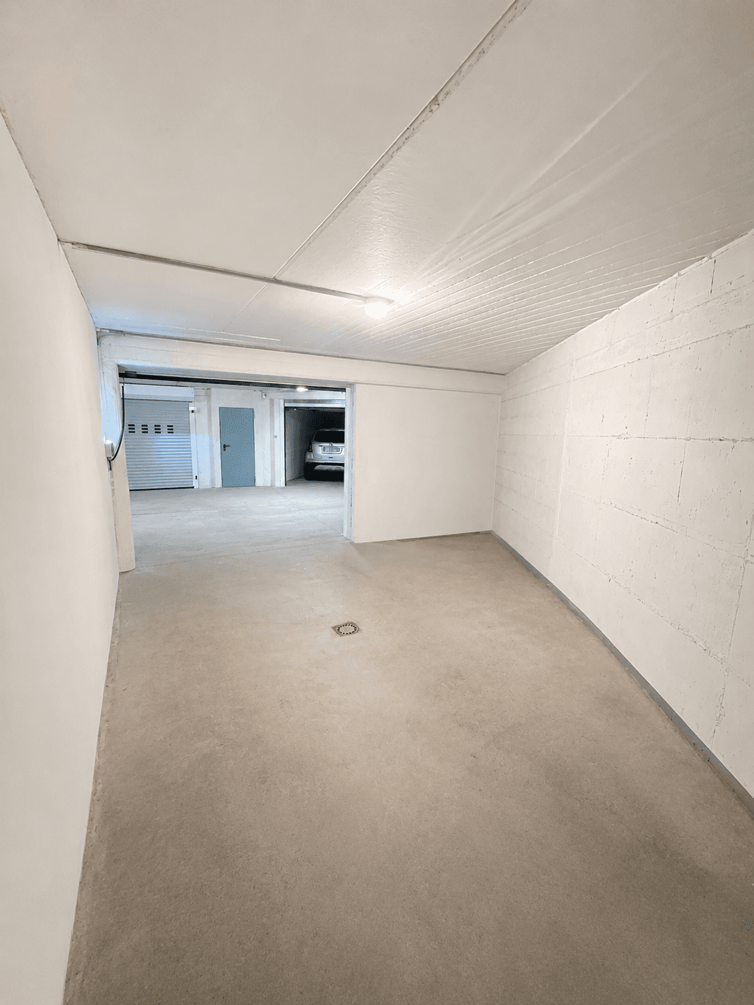 Geräumiger Kellerraum mit Betonboden und Zugang zu weiteren Bereichen.