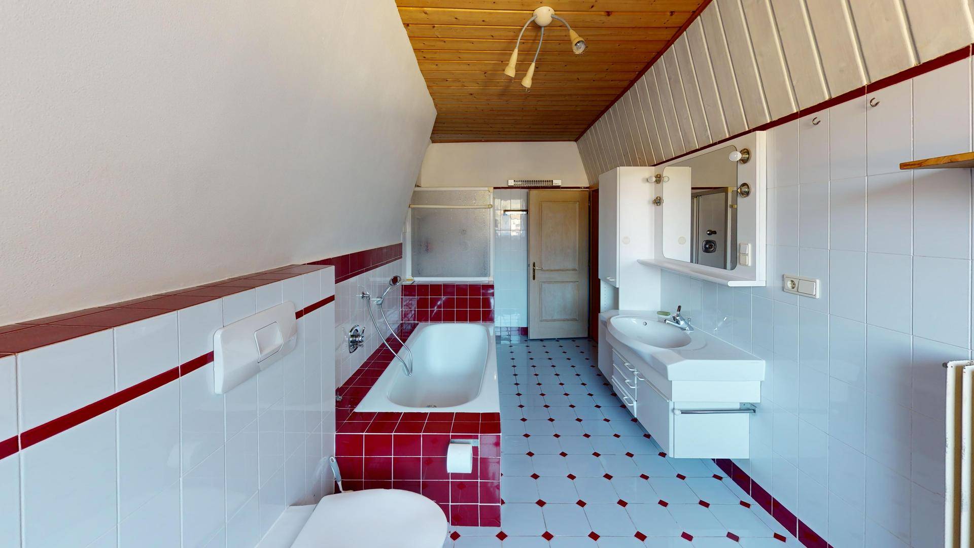 Badezimmer mit Badewanne, WC, Waschbecken und Spiegelschrank.