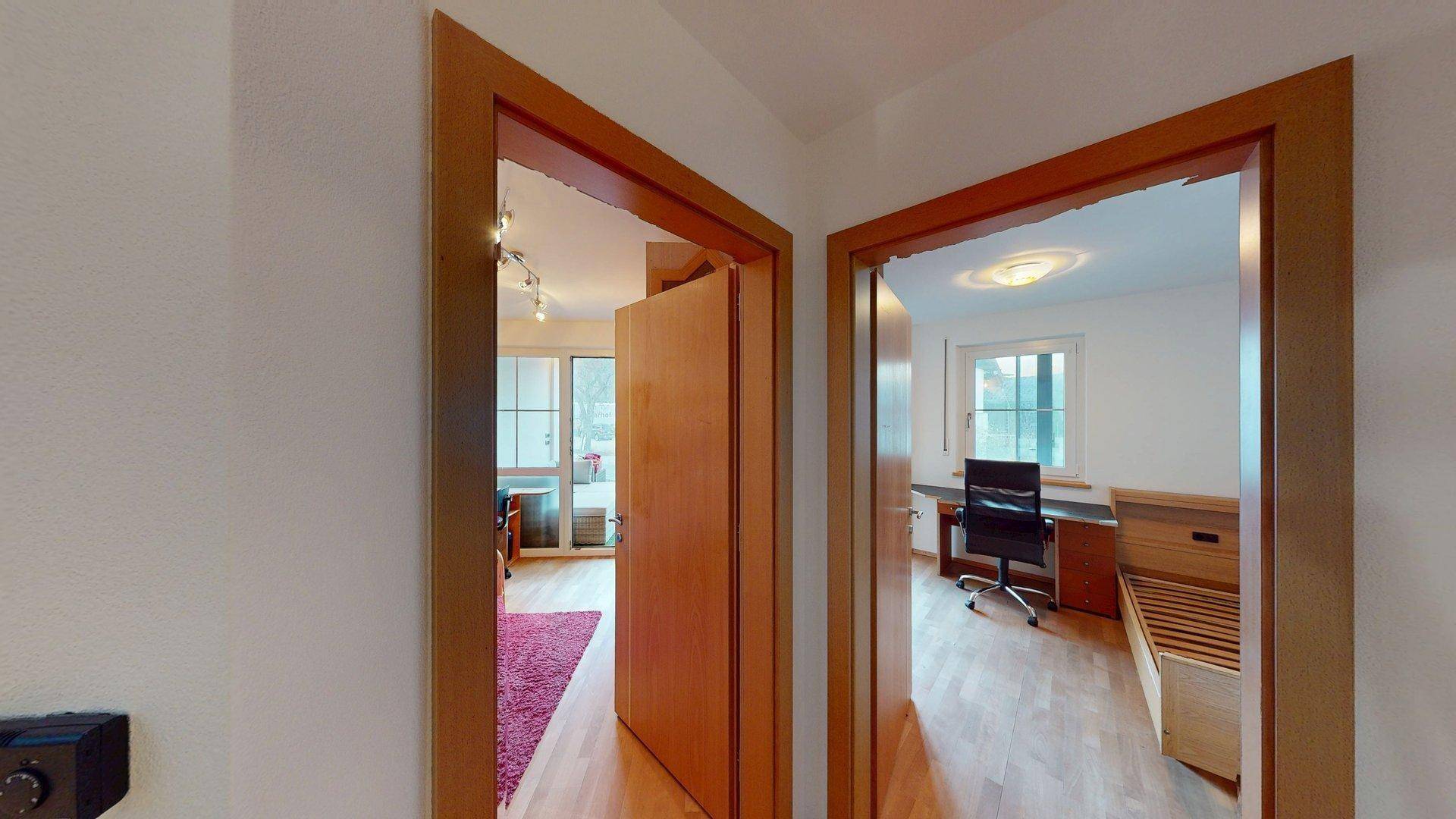 Heller Flur mit Holztüren, der den Zugang zu einem Wohnbereich und einem Schlafzimmer ermöglicht.