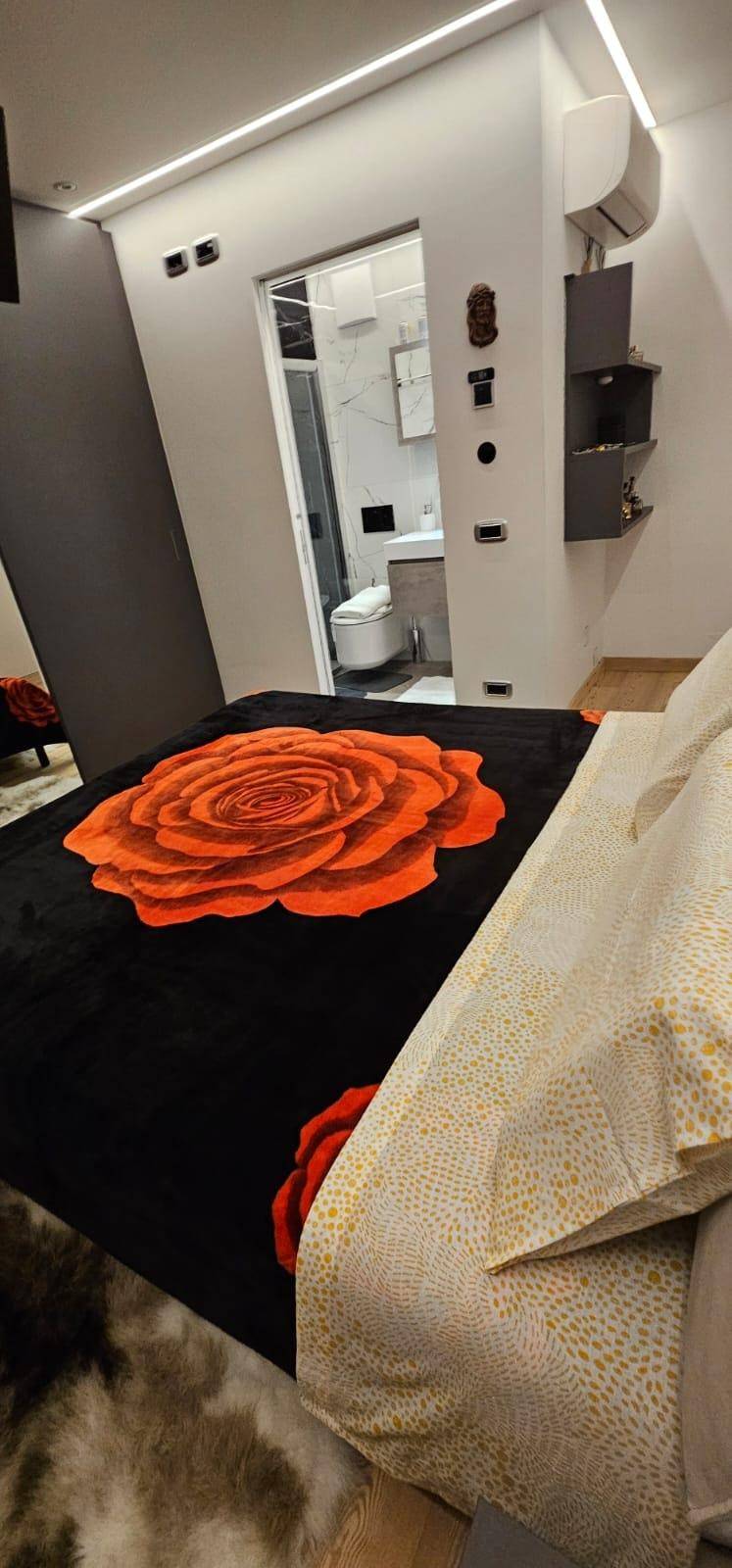 Schlafzimmer mit Blick auf das angrenzende moderne Badezimmer und indirekter Beleuchtung.