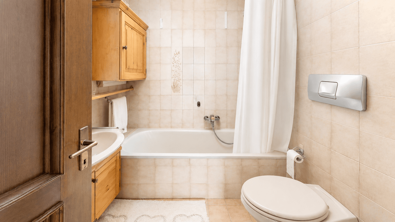 Funktionales Badezimmer mit Badewanne, WC, Waschbecken und beigen Fliesen.