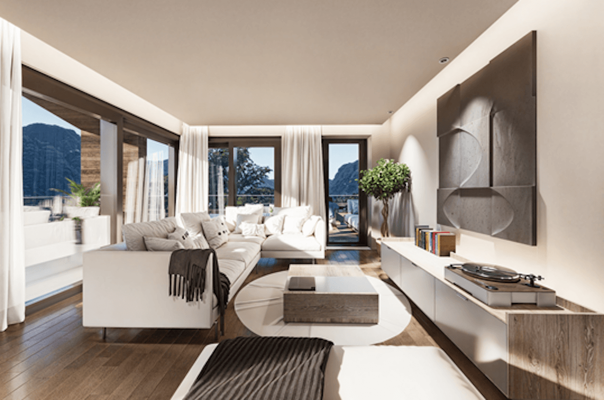 Helles, modernes Wohnzimmer mit weißem Sofa, Holzboden und Panoramablick auf die Berge.