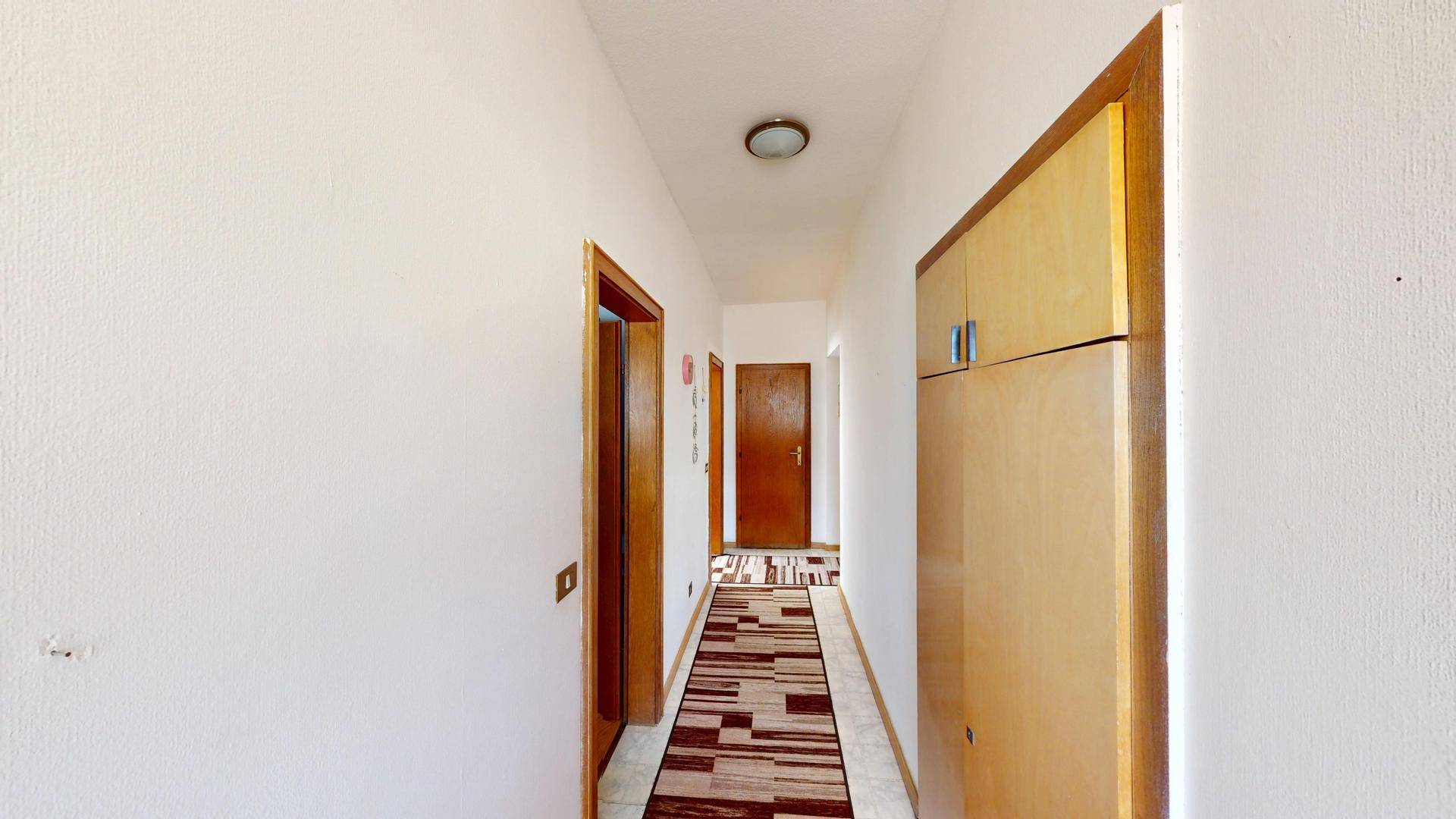 Flur mit einem Einbauschrank, Fliesenboden und Zugang zu weiteren Räumen.