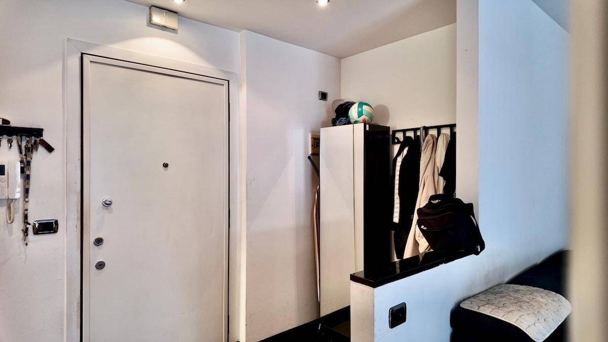 Eingangsbereich mit weißer Tür, Garderobe und Ablagefläche.