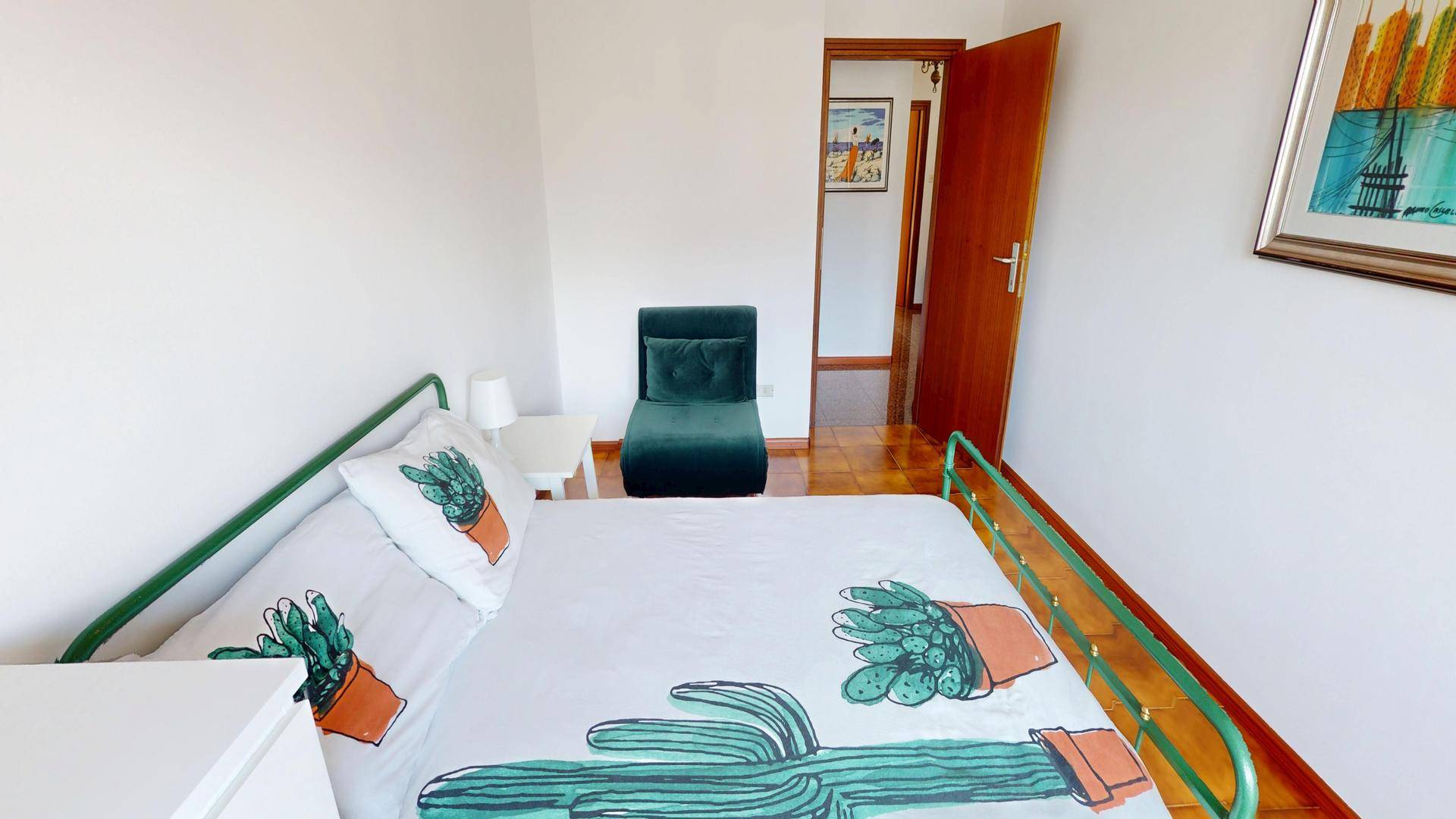 Schlafzimmer mit Einzelbett, Stuhl und Zugang zu einem weiteren Raum.