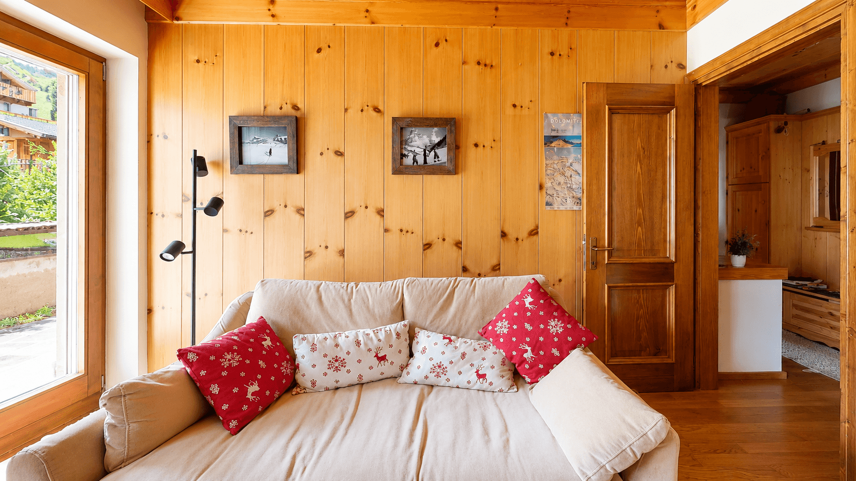 Helles Wohnzimmer mit bequemer Couch, Holzwänden und Zugang zum Außenbereich.