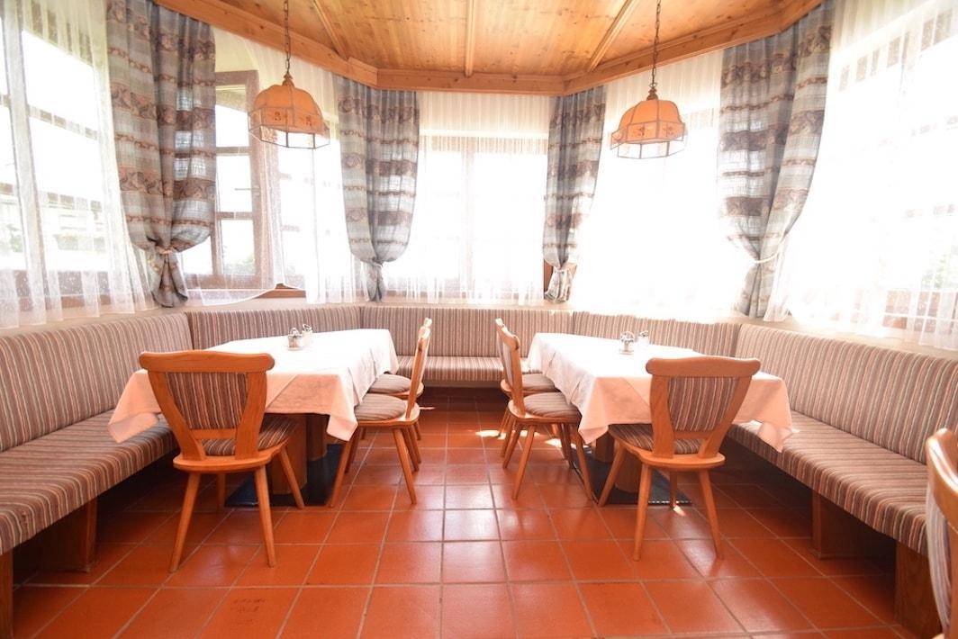 Gemütlicher Essbereich mit großer Eckbank, Holzbalkendecke und Terrakottafliesen.