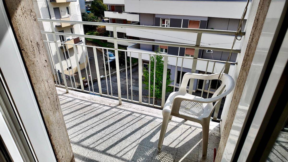 Balkon mit einem Plastikstuhl und Blick auf die umliegenden Gebäude.