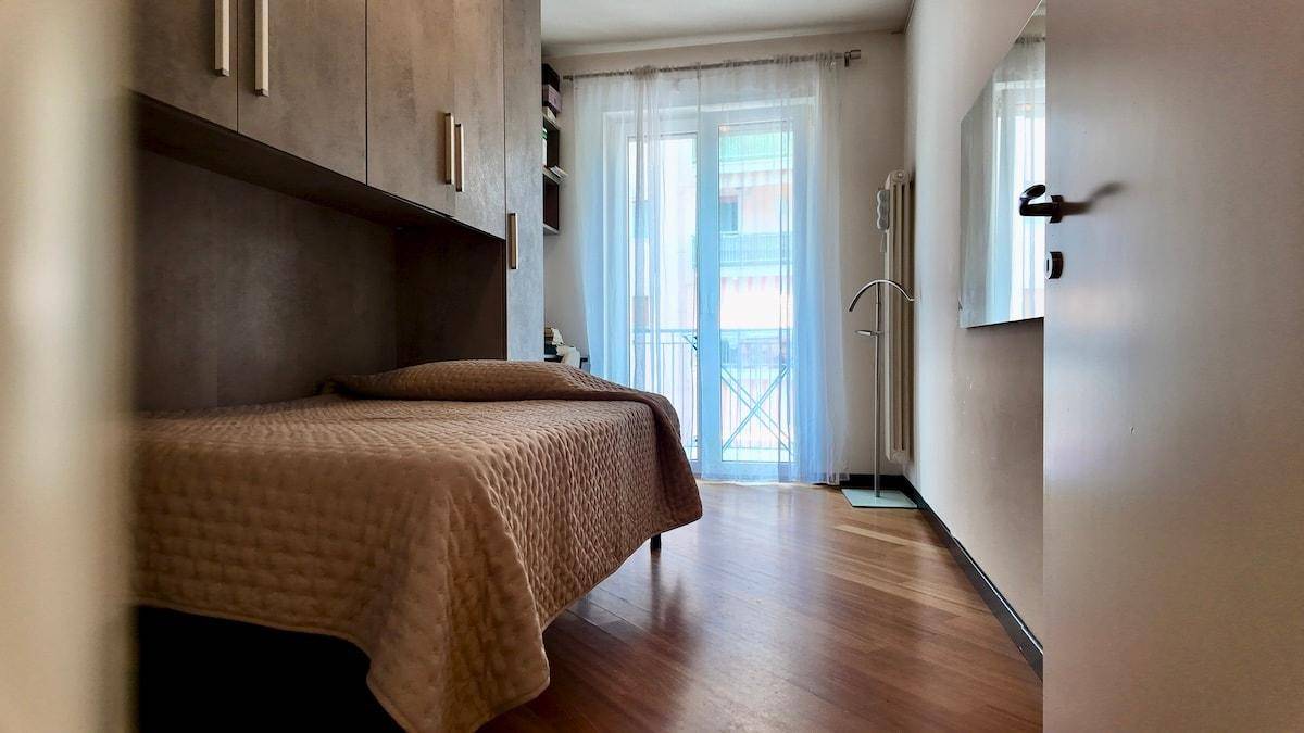 Schlafzimmer mit Einzelbett, Einbauschränken und Zugang zu einem französischen Balkon.
