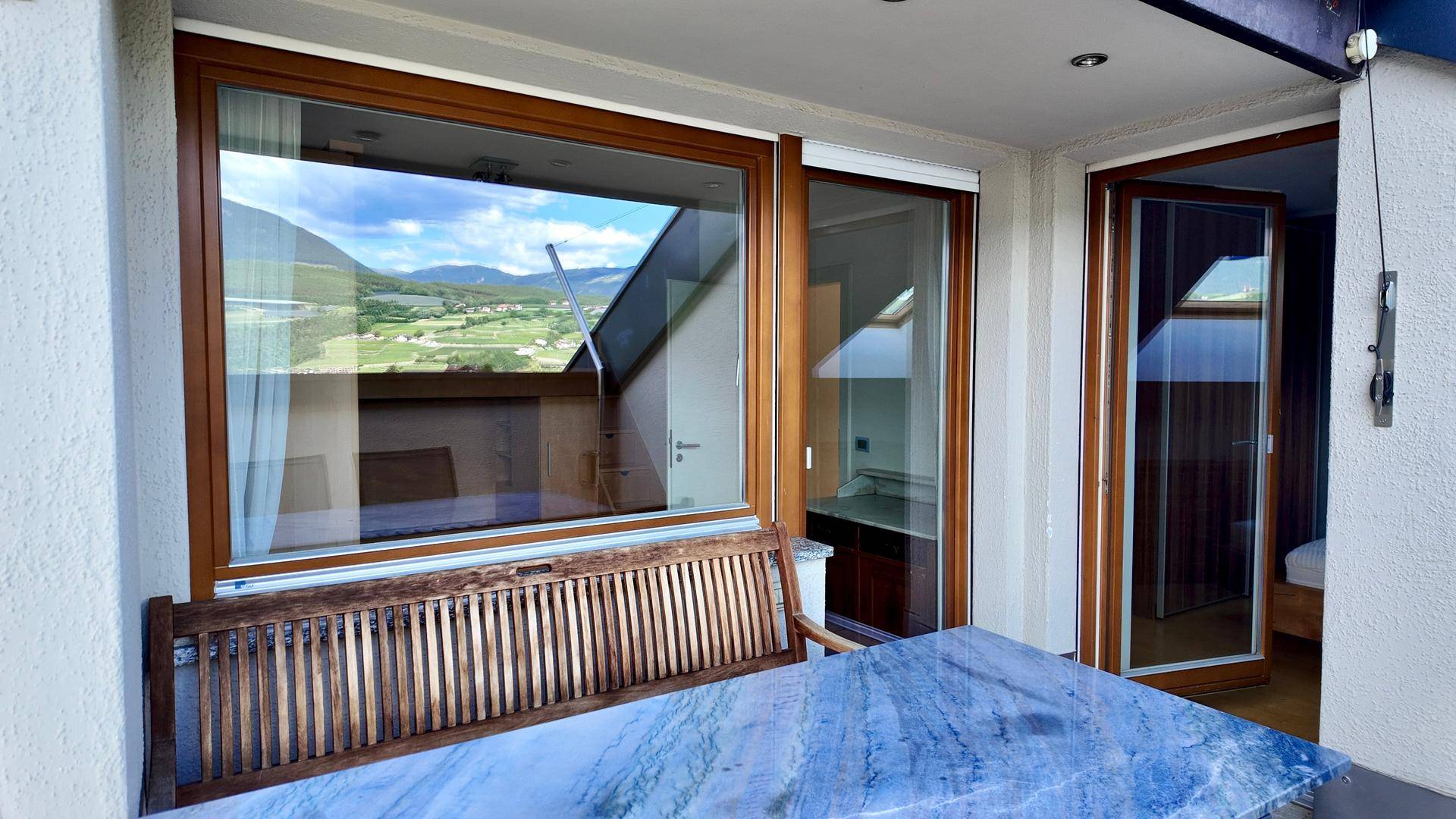 Überdachter Balkon mit Holzsitzbank und Tisch, bietet einen geschützten Außenbereich.