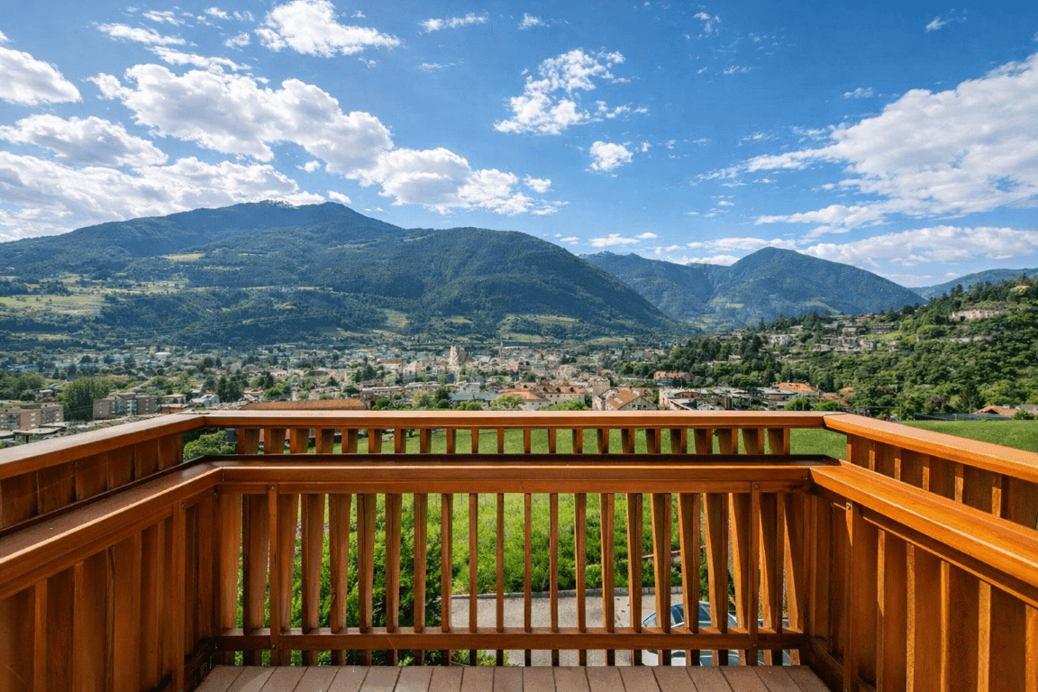 Balkon mit Holzgeländer und Panoramablick über die Stadt und die umliegenden Berge.