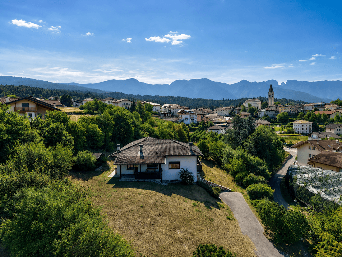 Haus in erhöhter Lage mit Blick auf ein charmantes Dorf und die umliegende Berglandschaft.