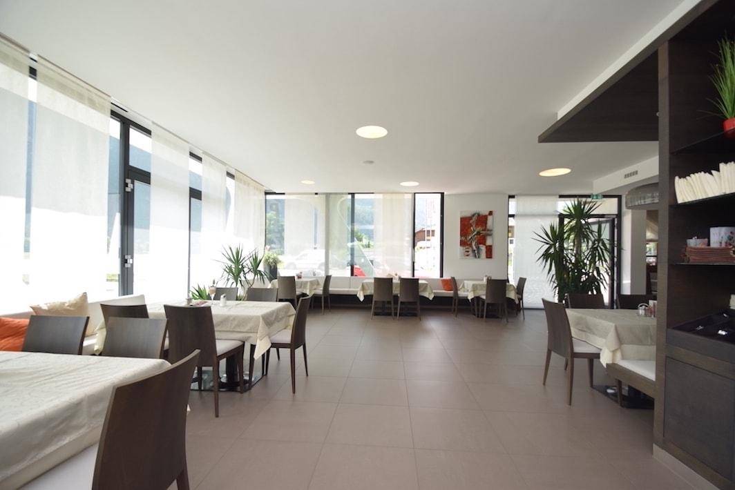 Heller Speisesaal mit großen Fenstern, die viel Tageslicht hereinlassen, und Pflanzen als Dekoration.