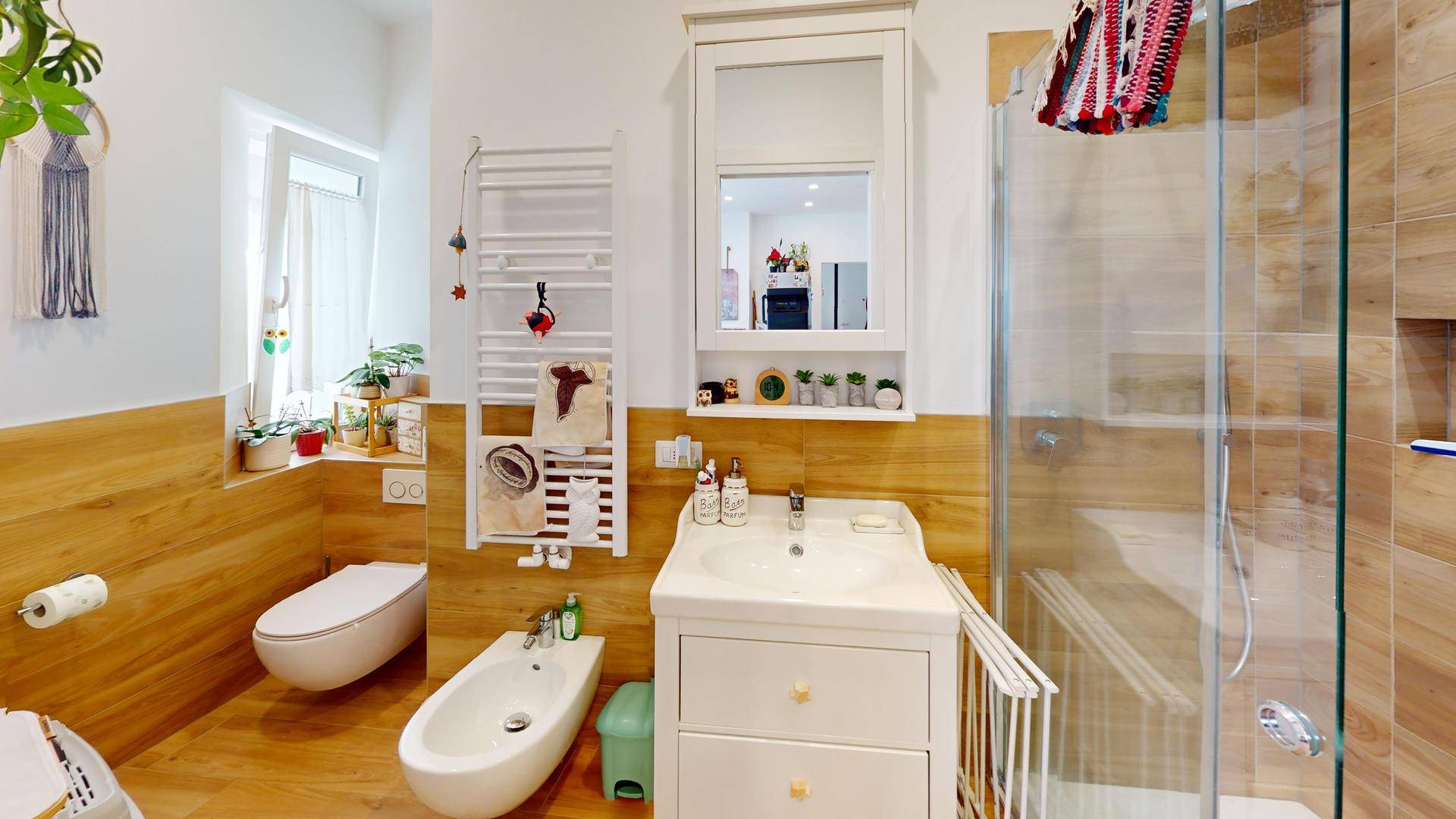 Modernes Badezimmer mit Dusche, WC, Bidet und Holzoptik-Fliesen.
