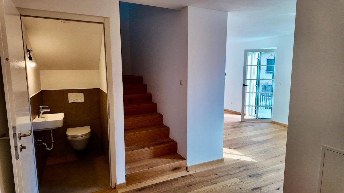 Eingangsbereich mit Holztreppe und Zugang zu einem modernen Gäste-WC.