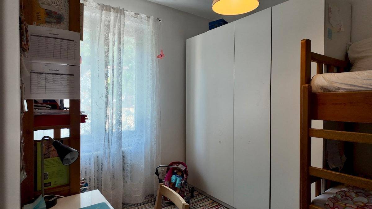 Kinderzimmer mit Etagenbett, Schreibtisch und weißem Kleiderschrank, gut beleuchtet.