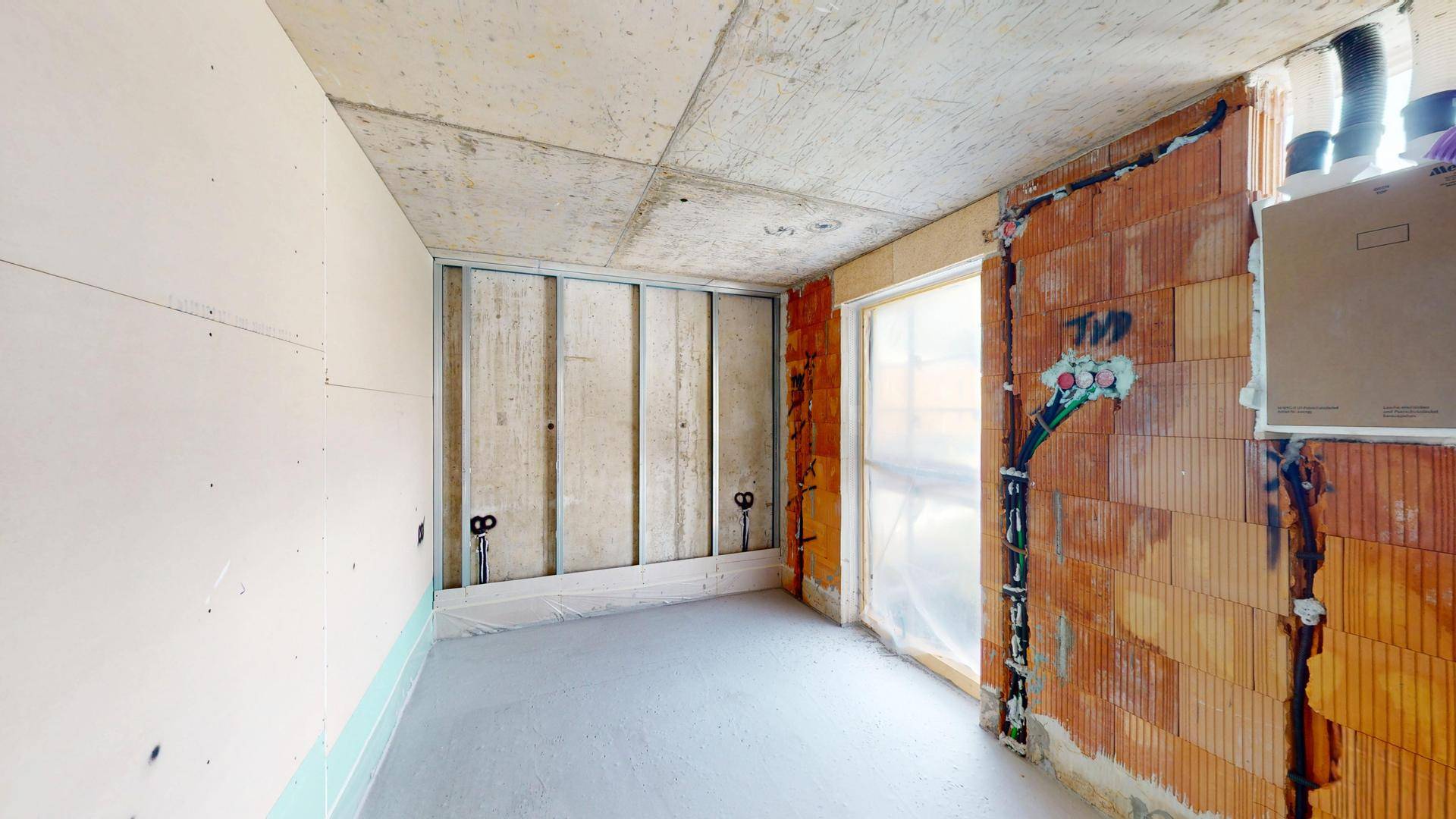 Innenraum im Rohzustand mit Betonwänden und Decken, bereit für den weiteren Ausbau.