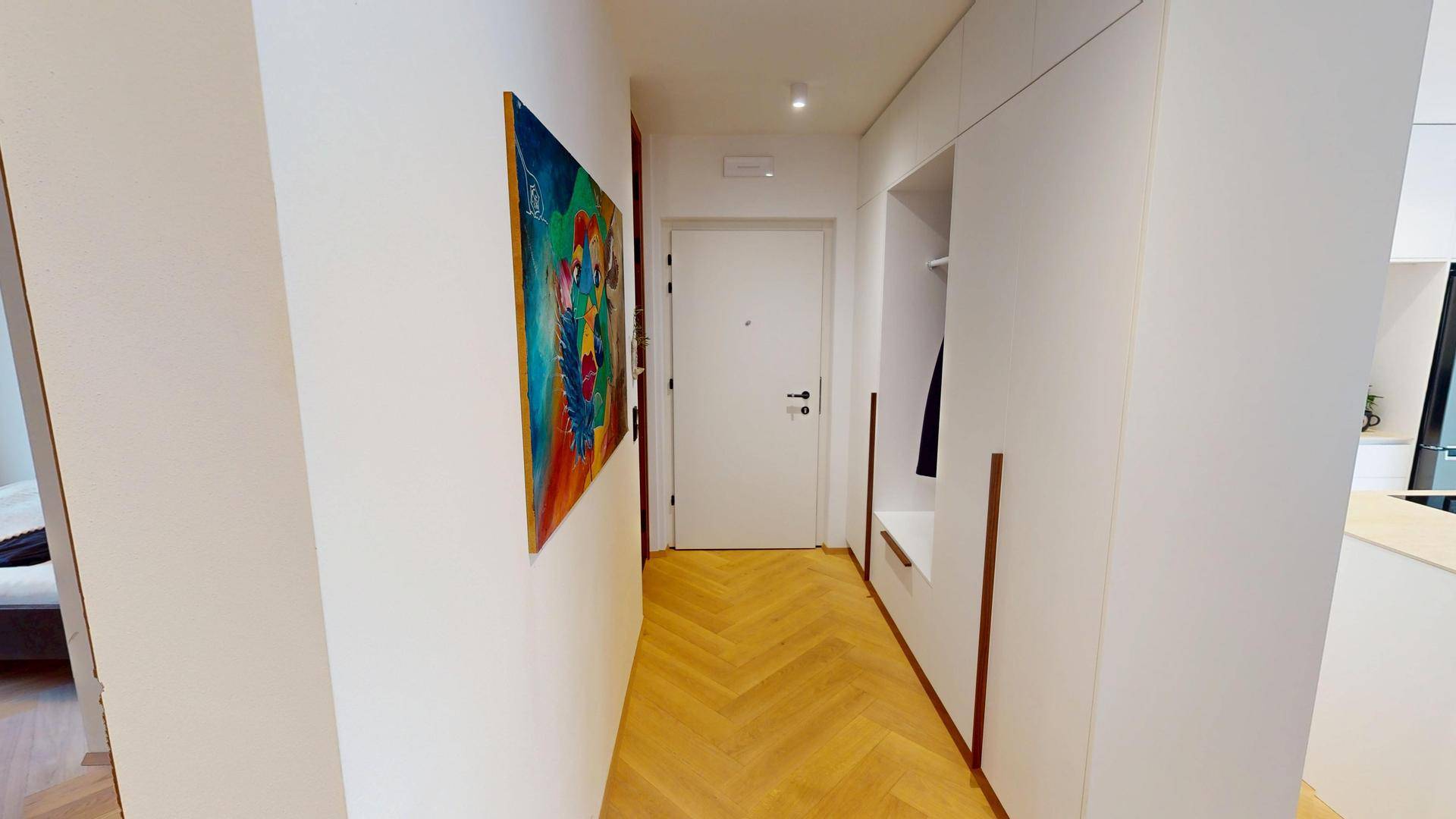 Heller Flur mit Garderobe, Holzboden und moderner Kunst an der Wand.