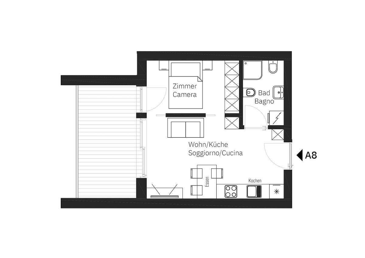 Grundriss einer Wohnung mit Schlafzimmer, Bad und offenem Wohn-/Kochbereich sowie Balkon.