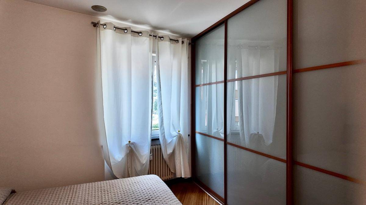 Schlafzimmer mit großem Schrank, Fenster und Holzboden.