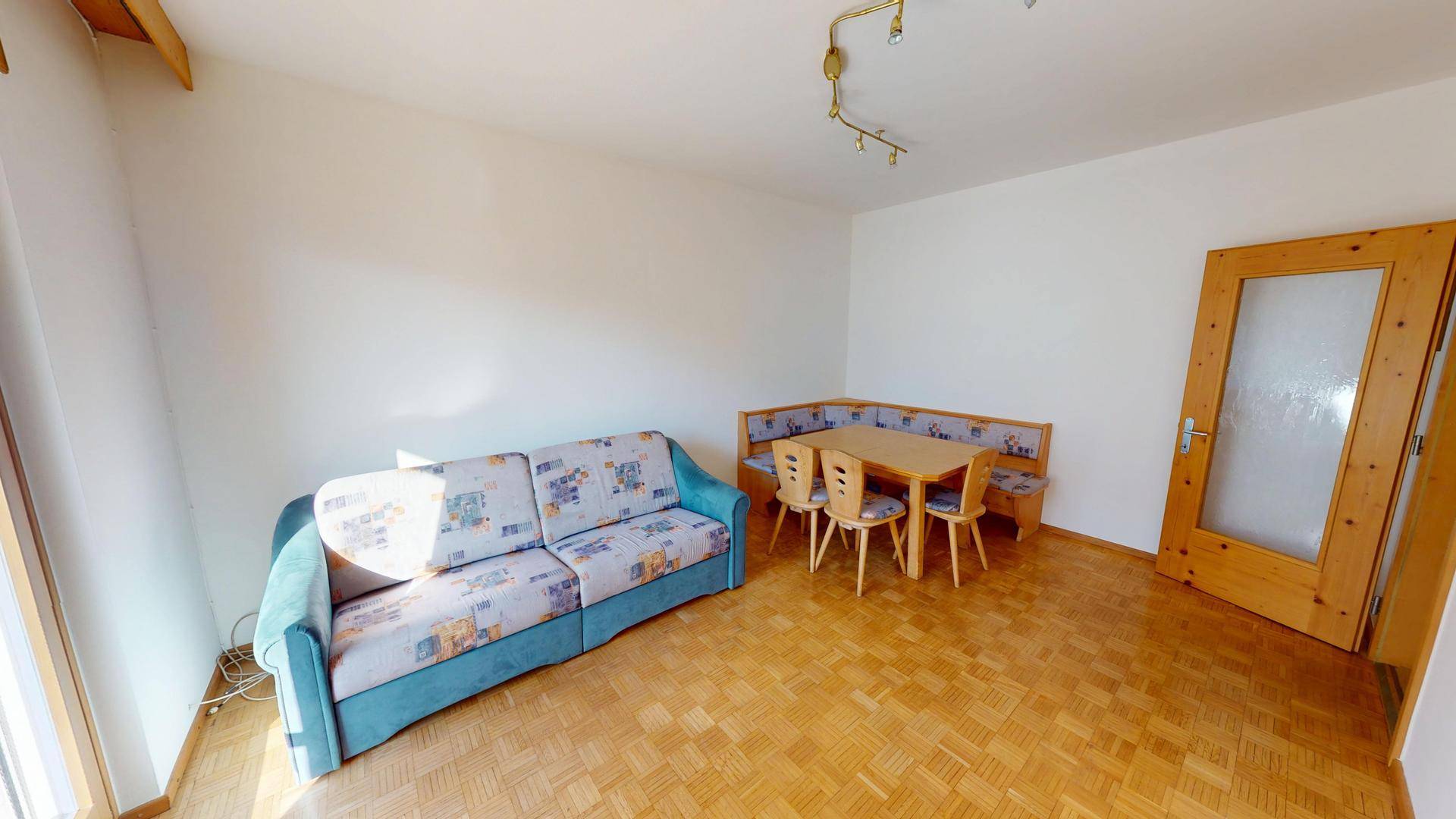 Wohnzimmer mit Sitzgruppe, Esstisch und Parkettboden.