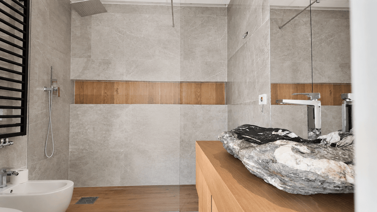 Modernes Badezimmer mit grauen Fliesen, Steinwaschbecken, Bidet und begehbarer Dusche.