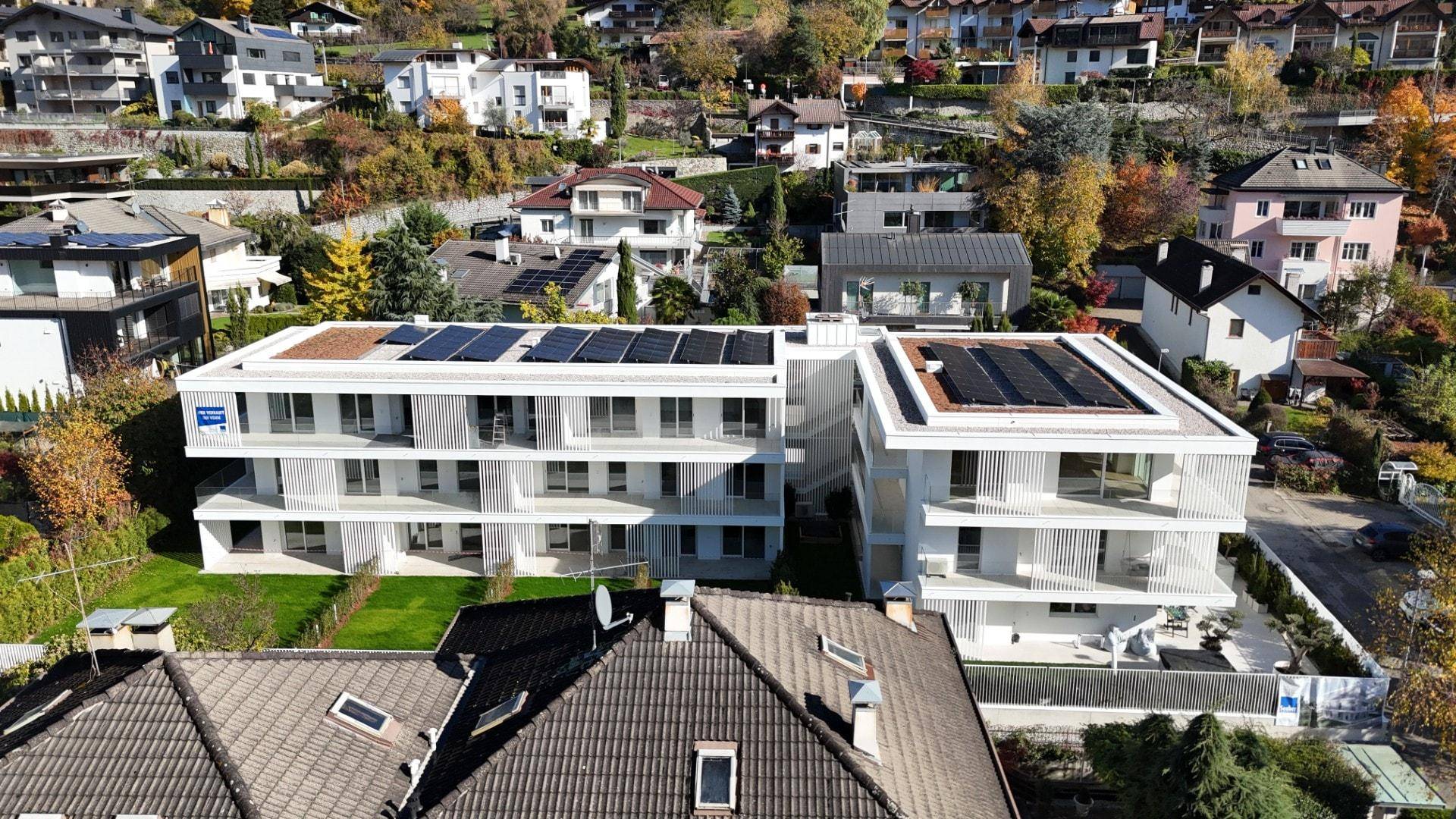 Vogelperspektive einer modernen Wohnanlage mit Solaranlagen und umliegenden Häusern.