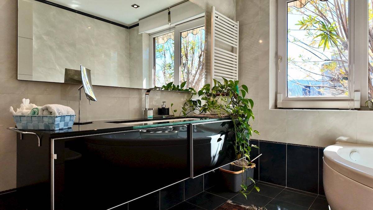 Modernes Badezimmer mit schwarzem Doppelwaschbecken, Badewanne und Fenster.