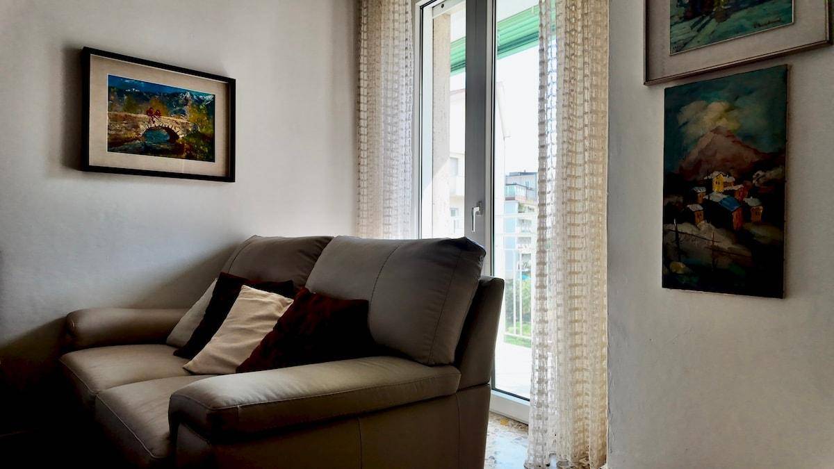 Helles Wohnzimmer mit beigem Sofa und Fenster, das viel Tageslicht hereinlässt.