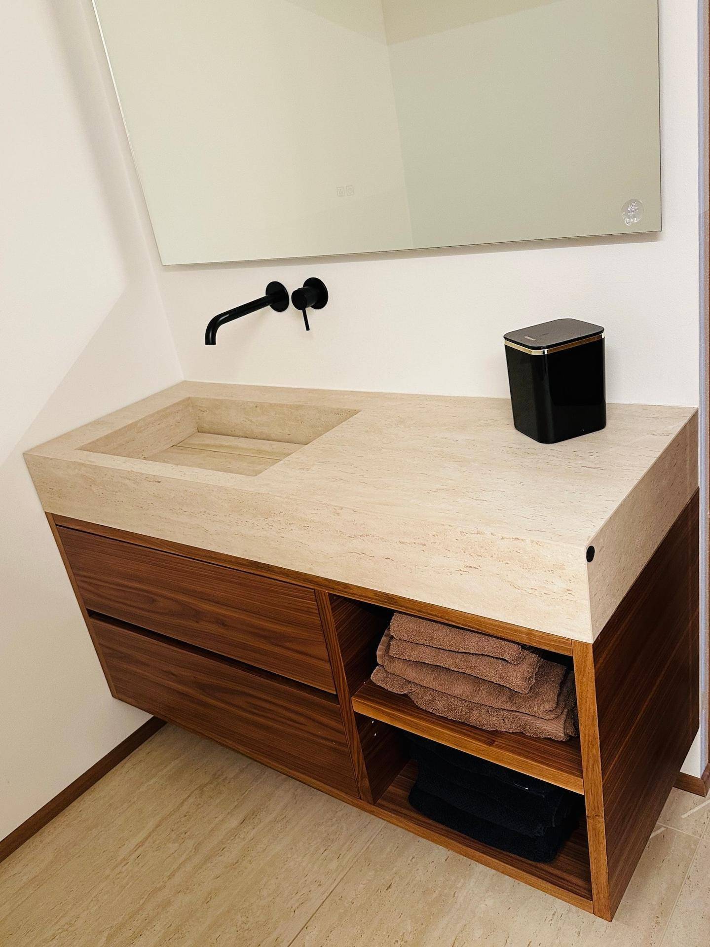 Modernes Badezimmer mit Waschtisch aus Naturstein und Holzunterschrank.