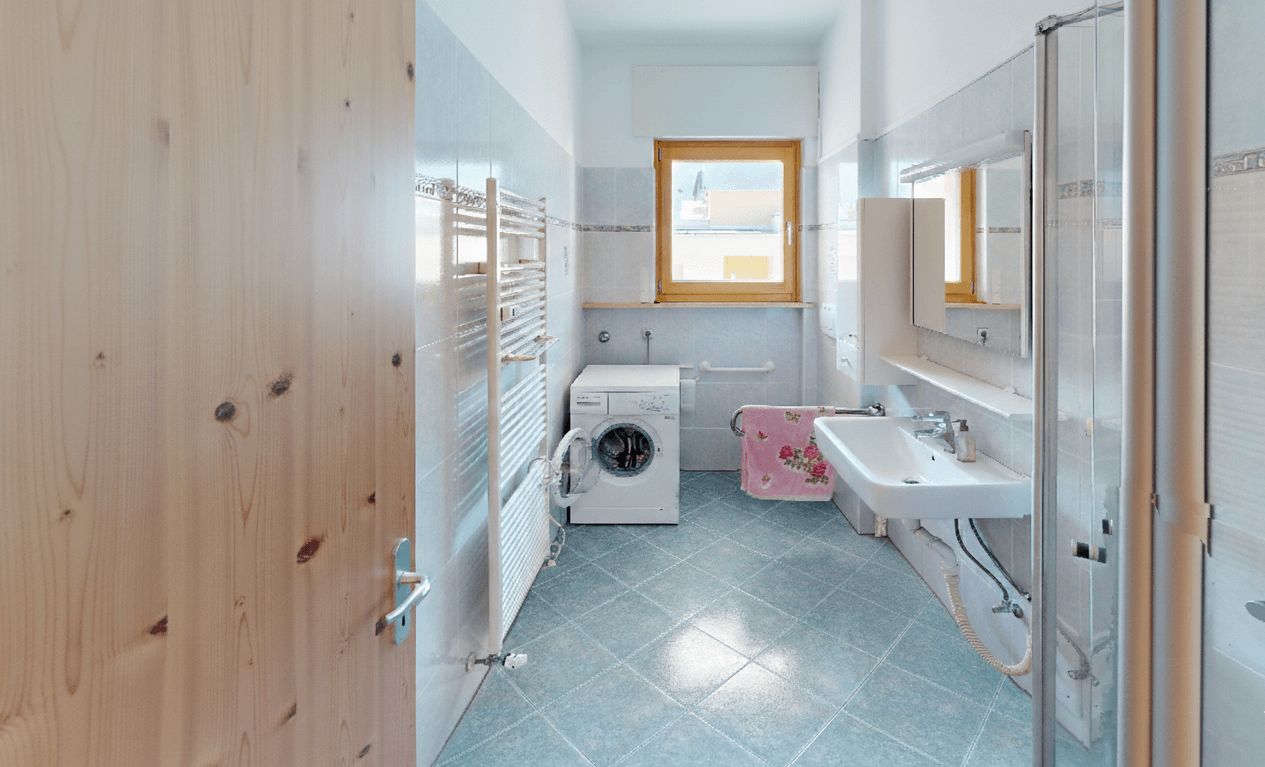 Badezimmer mit Dusche, Waschmaschine, Fenster und beheiztem Handtuchhalter.