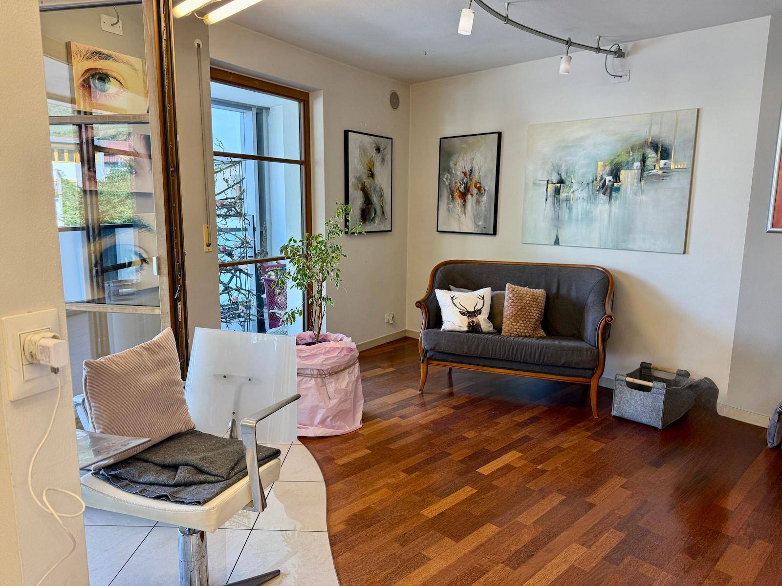 Heller Wartebereich mit bequemer Sitzgelegenheit, Kunst an der Wand und Fenster mit Ausblick.