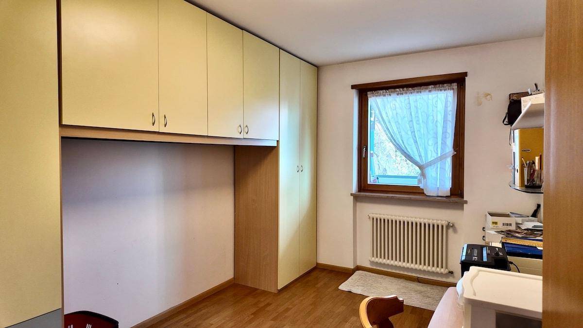 Schlafzimmer oder Kinderzimmer mit Einbauschränken, Holzfußboden und Fenster.