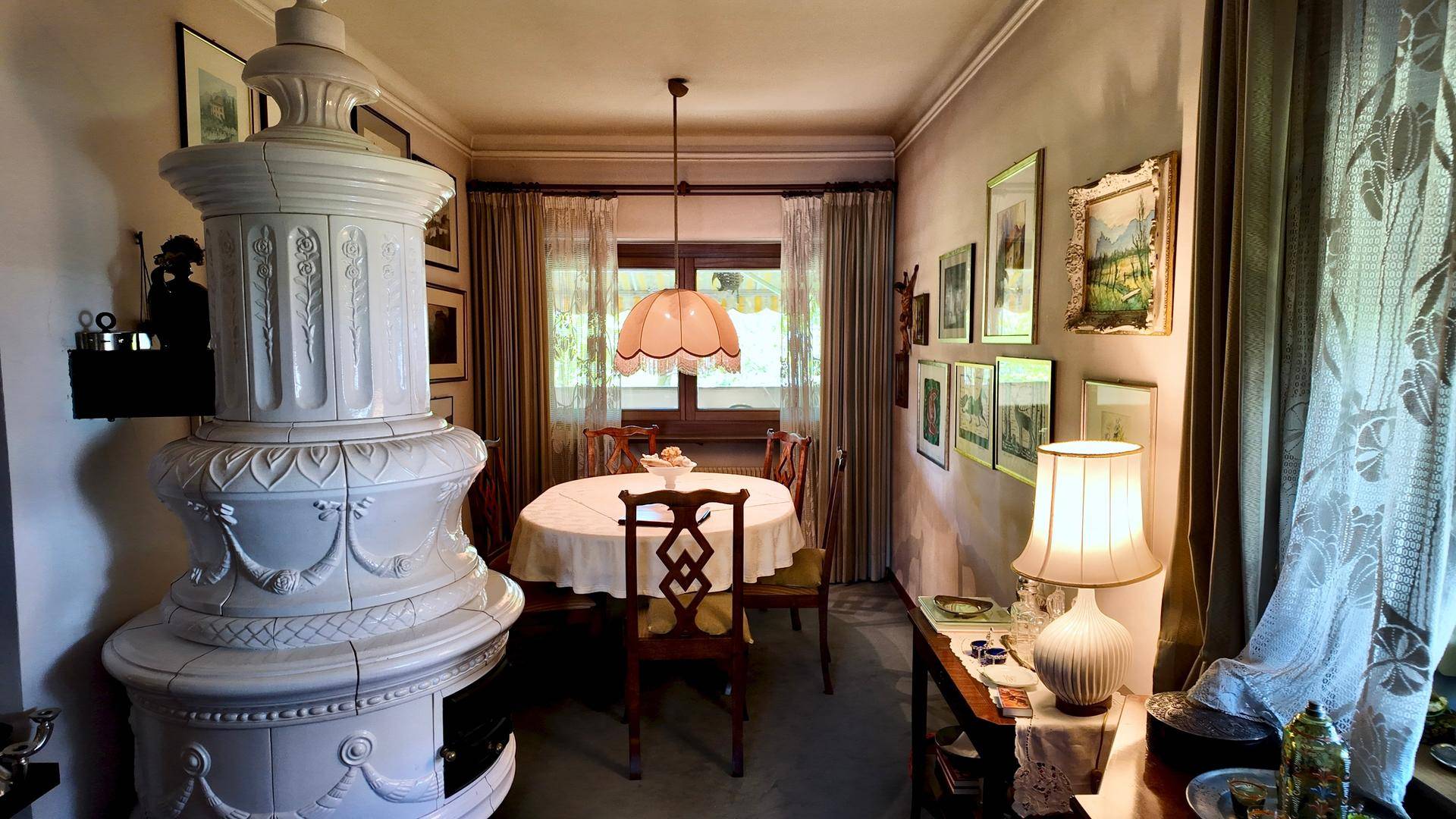 Elegantes Esszimmer mit Kachelofen, rundem Esstisch und klassischer Einrichtung.